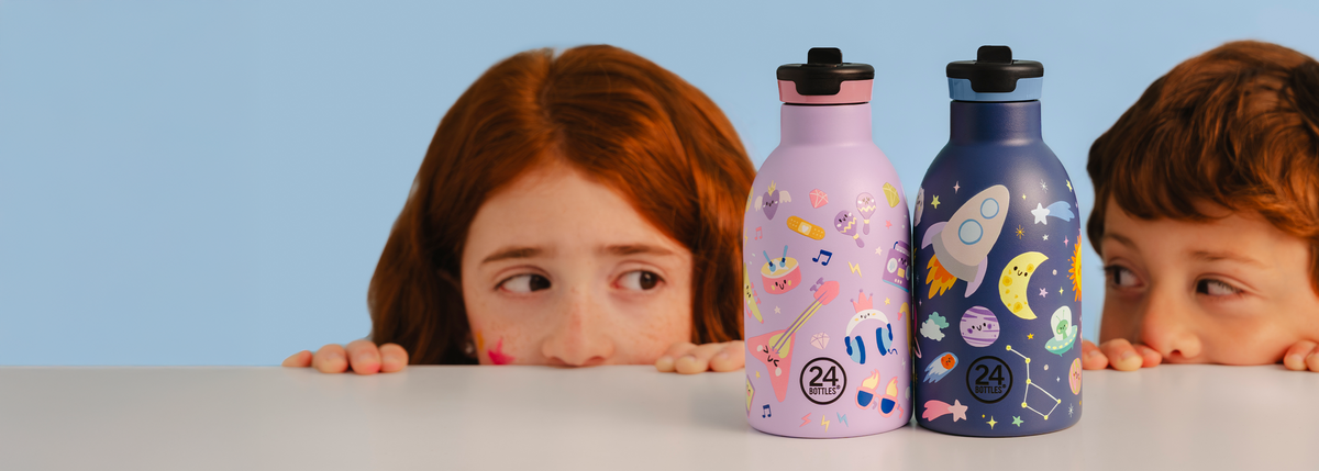 Two children behind two colorful water bottles (24Bottles Space Friends and Music Friends in the 330 ml size)
