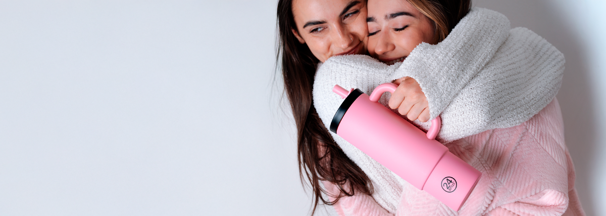 Two people hugging with a flamingo 24Bottles Straw cup between them.