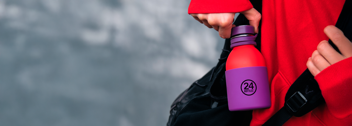 Person holding a red and purple water bottle with '24Bottles' logo on it